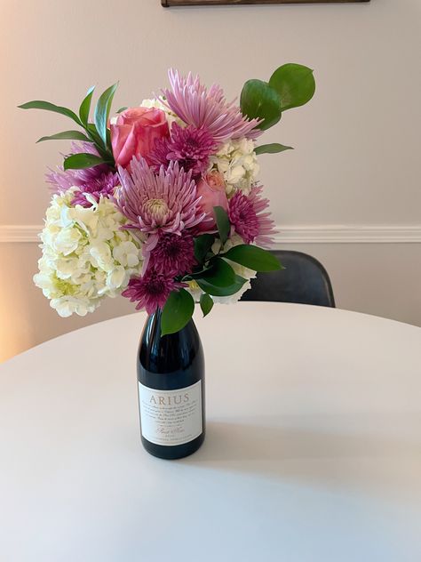 Centerpiece Wine Bottle, Flower Arrangement On Top Of Wine Bottle, Wine With Flowers On Top, Flower Bouquet With Wine Bottle, Flower Bouquet On Wine Bottle, Champagne Bottle Flowers Bouquet, Wine Bottle Floral Bouquet, Wine Floral Arrangements, Wine Bottle Centerpieces With Flowers