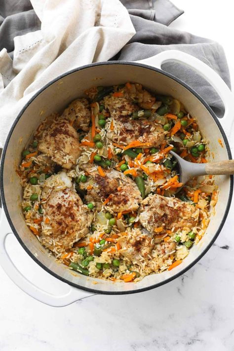 Juicy, perfectly seasoned chicken thighs combine with rice and veggies in this easy one pan dutch oven chicken and rice recipe. Only 15-minutes of active cooking time and 6 main ingredients for an easy and healthy weeknight dinner. It's seriously the best one pot chicken and rice recipe! It's great for leftovers, meal prep and freezer friendly. Dutch Oven Recipes Healthy Clean Eating, High Protein Dutch Oven Recipes, Chicken And Rice Dutch Oven Recipes, One Pot Chicken Thigh Recipes, Chicken Thighs Dutch Oven, Dutch Oven Rice, Dutch Oven Chicken And Rice, Healthy Dutch Oven Recipes, Chicken Rice And Veggies