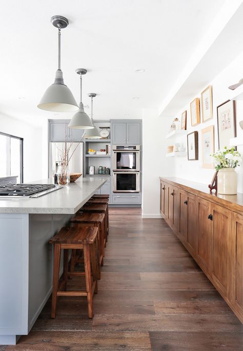 Rustic inspired kitchen with dark wood floors, a light gray island, and gray pendant lights and wood barstools Long Narrow Kitchen, Design Grill, Narrow Kitchen, Rustic Kitchen Design, Dark Wood Floors, Cheap Home Decor, Rustic Kitchen, Home Decor Kitchen, White Kitchen