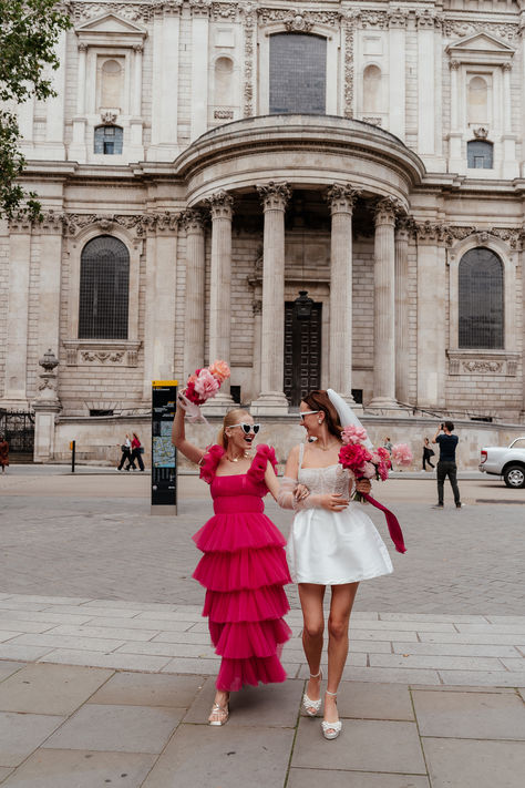 Bride wearing a short wedding dress with short veil with bridesmaid in hot pink layered ruffle tulle dress in matching white retro heart sunglasses | pink wedding theme | city wedding | Emma Olivia Colorful Short Wedding Dress, Retro Short Wedding Dress, Short Pink Wedding Dress, Wedding Dress With Short Veil, Pink Short Wedding Dress, Short Dress Long Veil, Mod Bride, Pink Retro Wedding, Hot Pink Wedding Theme