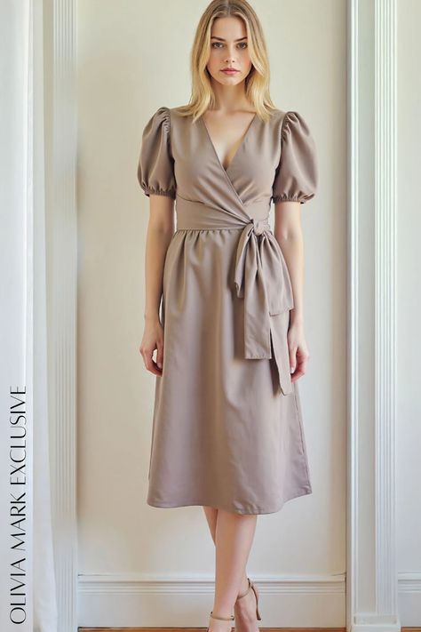 Its taupe hue is both timeless and versatile, making it a wardrobe staple that effortlessly transitions from day to night. The V-neckline adds a touch of allure, while the puff sleeves and cinched waist create a silhouette that is both flattering and feminine. The fabric drapes gracefully, accentuating your curves and lending a sense of movement that is both captivating and graceful. This dress is not just an article of clothing; it is a statement of style, a celebration of femininity, and a testament to the enduring beauty of simplicity. Dress With Puffed Sleeves, Wrap Midi Dress, Draped Fabric, Puffed Sleeves, An Article, Cinched Waist, Olivia Mark, Puff Sleeves, Elegant Dresses