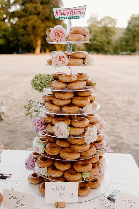 Krispy Kreme doughnut tower complete with floral decor Krispy Kreme Donut Tower, Wedding Cake And Doughnut Display, Doughnut Cake Tower, Donut Hole Tower, Krispy Kreme Wedding, Glazed Donut Cake Tower, Birthday Doughnut, Doughnut Tower, Prosecco Wall