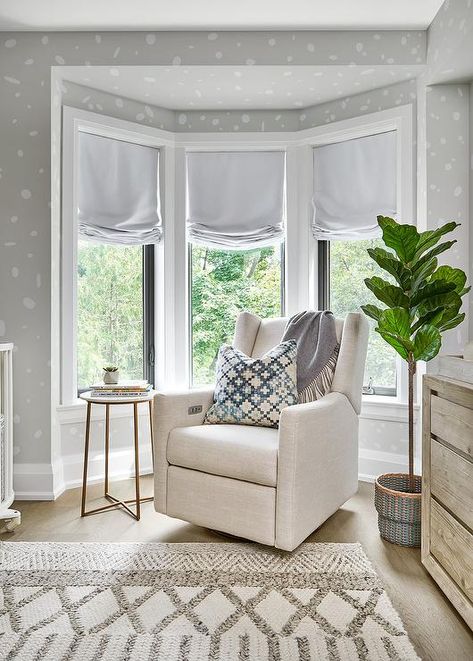 Contemporary nursery with a bay window furnished with an ivory wingback rocker and a fiddle leaf fig plant. White And Gray Curtains, Bow Window Ideas Living Room, How To Decorate A Bay Window, Light Grey Painted Walls, Decorating A Bay Window, Black Curtain Rod, Pink Velvet Curtains, Fiddle Leaf Fig Plant, Gray Curtains