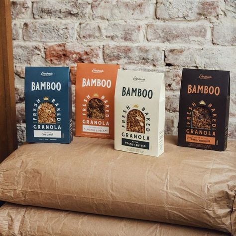 Four cereal boxes sit atop a grain bag in front of a rustic brick wall. From left to right, they are blue, orange, white, and black. Each box reads Handmade Breakfast bamboo Fresh-Baked Granola, and then the flavor of each package.. In the center of each box is an arch cut out showcasing the granola product inside. The text wraps around the top of this arch. Granola Packaging Design, Granola Packaging, Granola Brands, Fresh Food Packaging, Grocery Aisle, Breakfast Granola, How To Make Granola, Granola Aesthetic, Brand Packaging Design