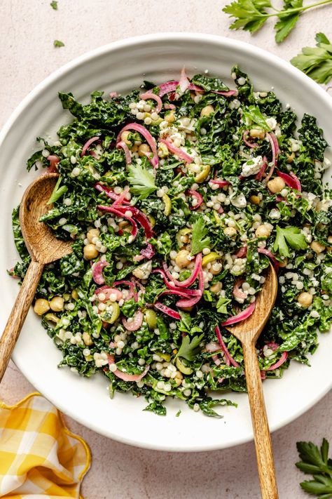 Fresh, herby kale couscous salad with feta, chickpeas, and olives that comes together in just 30 minutes for a satisfying lunch or side dish. Scoop up this beautiful salad with tortilla chips or pitas chips to get an extra delicious crunch! You'll love this veggie-packed salad as is or with your favorite grilled proteins. Ambitious Kitchen Kale Couscous Salad, Kale And Couscous Recipes, Lemon Herb Couscous Salad, Plant Based Salads Healthy, Trendy Salads, Salad Ideas Aesthetic, Scoopable Salad, Couscous Salad Recipes Cold, Prepped Salads