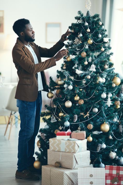 A well-dressed man decorating the Christmas tree next to gifts Christmas Tree Photos, Christmas Tree At Home, Decorating Christmas Tree, Decorating The Christmas Tree, Tree Photos, Christmas Tree Images, Photography Men, Single Man, Business Photoshoot