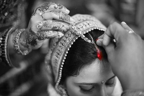 Putting sindoor in hair partition Red is the colour expressing power (Red is the colour which depicts the energy of Sati and Parvati in Indian mythology. Sati is said to be an epitome of ideal Hindu wife who can even sacrifice her life for her husband’s sake. Hindus believe that putting vermillion will bless a woman with ‘Akhand Soubhagya’ from Goddess Parvati.) Sindoor control BP  Sindoor keeps woman calm and healthy Scientifically, a woman puts vermillion where her Ajna Chakra or Brahma Sthana Sindoor Moment Quotes, Sindoor Moment, Indian Wedding Pictures, Indian Wedding Poses, Bride Photos Poses, Marriage Photography, Indian Wedding Photography Couples, Bridal Photography Poses, Indian Wedding Couple Photography