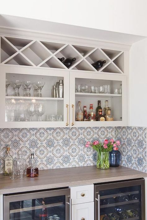 Glass built-in wine wrack above glass front cabinets accented with brass pulls in a bar nook featuring white and blue mosaic backsplash tiles. Bar Nook, Accent Tiles, Built In Wine Rack, Peony Pattern, Home Bar Rooms, Transitional Dining Room, Bar In Casa, Casa Country, Glass Front Cabinets