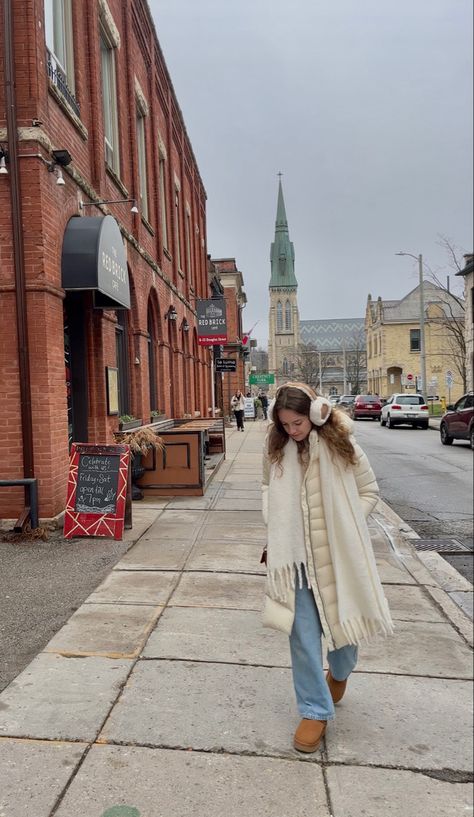 cream long puffer jacket and uggs and chunky white scarf with earmuffs scandinavian style and light wash jeans girl walking down road in European small town city White Puffer Jacket Outfit Winter, Cream Scarf Outfit, Cream Puffer Coat Outfit, Long Puffer Outfit, Cream Puffer Jacket Outfit, Long Puffer Coat Outfit, White Scarf Outfit, Cream Jacket Outfit, White Puffer Jacket Outfit