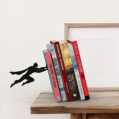 This superhero-themed bookend gives the impression of a superhero keeping your books up with the power of flight. A perfect gift for the book worm in your life! Superhero Bookends, Shelves Desk, Hidden Book, Decorative Bookends, Creative Books, Book Holder, Book Ends, Cool Books, Book Holders