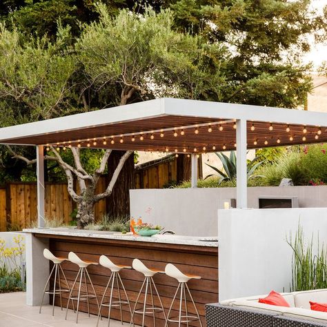 Outdoor bar:  Elaine Barden envisioned her #backyard retreat as “Palm Springs meets W Hotel style.” Her designers chose a custom fabricated aluminum arbor above an outdoor bar. The team built it on-site and painted it silver to match the wall sconces. Redwood slats cover the top. Diy Outdoor Bar, Bar Exterior, Outdoor Kitchen Bars, Outdoor Kitchen Appliances, Outdoor Remodel, Outdoor Dining Room, Backyard Bar, Casa Exterior, W Hotel