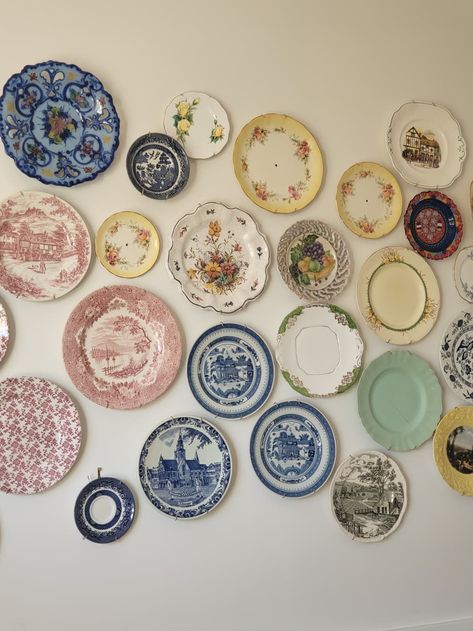 The vintage plates are all sourced from thrift stores.  Credit: Collette China Plate Gallery Wall, Decorative Plate Wall Display, Wall Of Plates Decor, Plates On Wall In Bedroom, Vintage Plate Wall Decor, Cute Plates Set, Vintage Coastal Kitchen, Thrift Decor Ideas Living Rooms, Cozy Thrifted Home