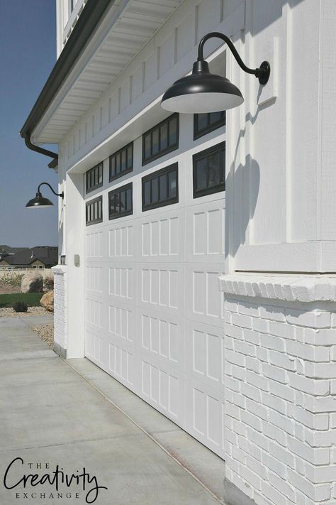 Modern farmhouse exterior lighting. White painted brick, white garage door, black detail and lighting. #exteriordesign White Garage Doors, Modern Garage Doors, Farmhouse Garage, Farmhouse Exterior Design, Garage Door Design, Modern Garage, Brick Exterior House, Modern Farmhouse Exterior, Exterior Remodel