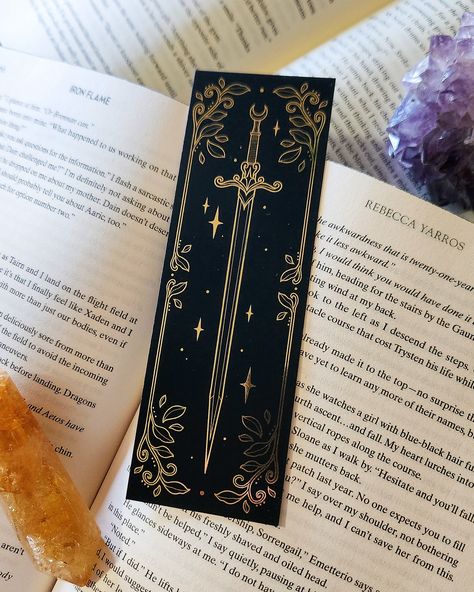 Some of you may have seen my story last week ✨ well here’s a look into the most gorgeous bookmarks that I designed 🗡️ there are three bookmark designs, two are gold foil and one is holographic foil. I’m absolutely floored with how stunning these are! They will be available on the 30th at noon! 💫🖤 #bookish #acotar #throneofglass Cool Bookmarks To Make, Gold Foil Bookmarks, Art Bookmark Ideas, Drawing Bookmarks Ideas, Cute Bookmarks Ideas, Bookmarks Diy Aesthetic, Bookmarks Printable Aesthetic, Aesthetic Book Mark Ideas, Cute Bookmark Ideas