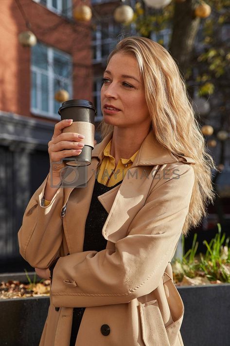 caucasian attractive woman in beige trench coat holding cup of coffee outdoors #Ad , #holding, #cup, #coffee, #outdoors Person Holding Soda Can Reference, Woman Holding Coffee Cup, Hand Holding Coffee Cup Drawing, Person Holding Coffee Reference, Holding Coffee Reference, Holding Cup Pose Reference, Life Model Reference, Holding Coffee Cup Reference, Person Holding Cup Reference