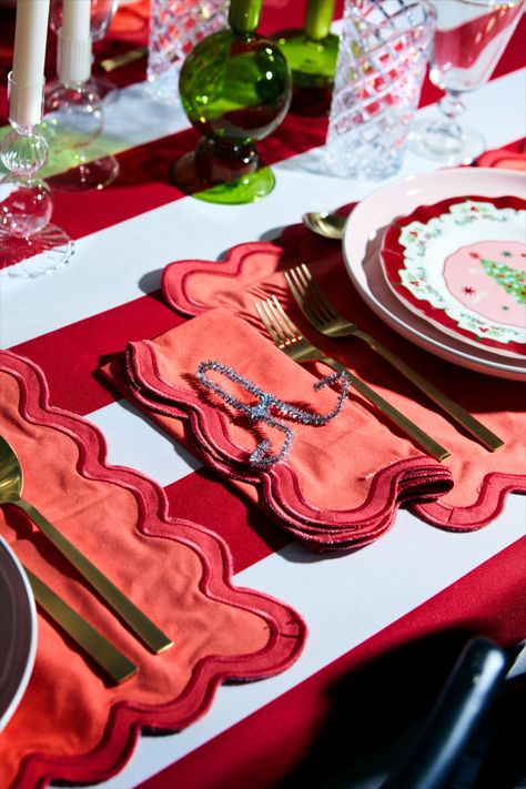 Christmas circus stripes? Yes, please! This red and white circus stripe tablecloth creates the perfect maximalist backdrop for our colorful pink and green vintage-inspired plates. We added more color to this retro Christmas tablescape by adding scalloped placemats, vintage glassware, and funky glass candle holders. Sticking with a specific color palette will let you experiment with textures and patterns without your Christmas table decorations feeling overwhelming. #colorfulchristmas #retro #bhg Fun Christmas Table Decorations, Red Green And Pink Christmas, Holiday Decor Aesthetic, Glam Christmas Party, Feeling Overwhelming, Scalloped Placemats, Christmas Circus, Maximalist Christmas, Colorful Table Decor