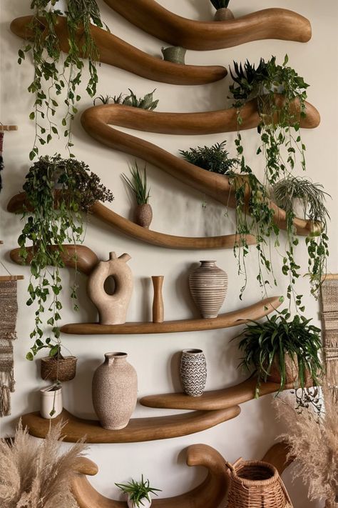 Design a Boho-chic statement wall using organic wooden shelving. Complement the warm tones with cascading plants, earthy textures, and sculptural details to create a harmonious, inviting space. #WoodenShelving #StatementWall #BohoHomeDecor #OrganicDesign #CascadingPlants #EarthyCharm #WovenAccents #GreeneryInspiration #InteriorStyling #DecorGoals Curved Wall Decor Ideas, Modern Earthy Home Decor, Nature Inspired Furniture, Earthy Wall Decor, Nature Shelf, Wabi Sabi Boho, Earth Decor, Cascading Plants, Boutique Hotel Lobby