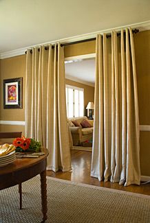 Curtains add glamour, increase privacy, buffer noise, and block drafts. Here, the entrance from the dining area to the den is framed with thick, textured panels hung from a simple rod mounted near the ceiling. Basement Suite, Curtain Divider, Partition Ideas, Partition Designs, Fabric Room Dividers, Wall Partition, Glass Room Divider, Bamboo Room Divider, Sliding Room Dividers