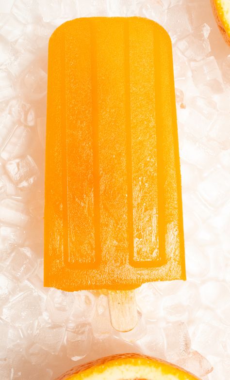 An orange popsicle lays on a bed of pebble ice on a white background. Wine Gummy Bears, Healthy Ice Pops, Orange Popsicles, Homemade Crunchwrap, Raspberry Pancakes, Dessert For Summer, Ice Pop Recipes, Cookie Recipes Chewy, Summer Popsicles