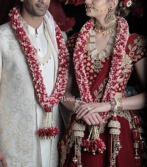 The significance of garlands in South Asian weddings lies in their symbolic representation of acceptance, love, and respect. Color Pop Wedding, Varmala Designs, Pink Bridal Lehenga, Indian Wedding Garland, Red And White Outfits, Red Garland, Garland Design, Indian Bridal Sarees, Couple Wedding Dress