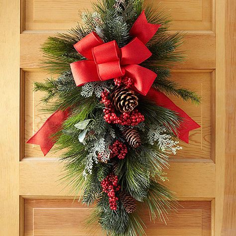 Studded with red berries and topped with a big red bow, this swag is sure to become a much-loved Christmas classic. For fullness, a long-needle teardrop-shape base anchors the holiday door arrangement. Holiday Door Decorations, Diy Christmas Door, Christmas Swag, Christmas Wreaths Diy Easy, Swag Wreath, Christmas Door Wreaths, Christmas Classic, Holiday Door, Mardi Gras Party