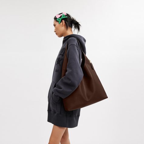 Our Brooklyn is an elegant minimalist silhouette—with a distinctly New York attitude. Crafted of natural grain leather with beautiful texture and soft feel this generously sized hobo style features a spacious interior with room for a 15” laptop and a snap pocket for access to essentials. The streamlined 39 is finished with a comfortable wide shoulder strap and an easy magnetic snap closure. | Coach Brooklyn Shoulder Bag 39 - Women's Purses - Brass/maple Coach Hobo Bags Outfit, Coach Brooklyn Shoulder Bag 39, Brooklyn Coach Bag, Suede Shoulder Bag, Coach Brooklyn 28, Leather Shoulder Bag Outfit, Coach Brooklyn Shoulder Bag, Hobo Bag Aesthetic, Laptop Bag Aesthetic