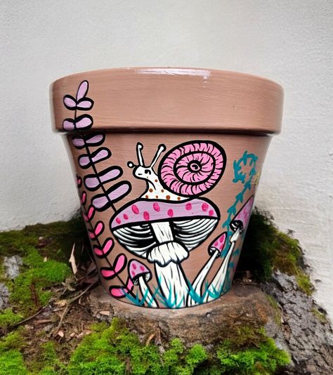 From within the wonderful world of imagination comes the "Snail Mushroom Garden", a hand painted terracotta pot, pretty enough so it makes it perfect for housing any plant. It makes a perfect gift for mushroom and witchy colors lover,.  This is a high quality pot made in Italy and the paint is water-based, eco-friendly acrylic to keep your plants safe and happy. MATERIALS AND CARE Hand-painted, terracotta planter, wipe clean only, water resistant, preferably indoor use only. This pot has drainag Spooky Painted Pots, Witchy Painted Pots, Diy Painted Planters, Painted Planter Ideas, Cute Painted Flower Pots, Painted Pot Designs, Painted Plant Pot Ideas, Diy Painted Pots Ideas, Flower Pots Painting Ideas