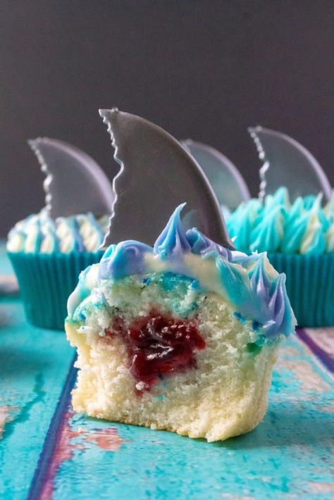 Shark Week Cupcakes are easy to make, fun to eat and the perfect sweet treat to sink your teeth into. Homemade orange cupcakes filled with a bite of rasberry orange sauce, these Shark Week Cupcakes are great for viewing parties, days at the beach or watching your favorite shark show on TV. | A Wicked Whisk #sharkweekcupcakes #sharkweekfood #sharkweekparty #sharkweekfoodideas #sharkweekfoodrecipes #sharkweekdesserts #sharkattackcupcakes Shark Week Cupcake Ideas, Shark Theme Cupcakes, Diy Shark Cupcakes, Shark Week Cupcakes, Shark Cupcakes Kid Birthdays, Shark Pull Apart Cupcakes, Shark Week Desserts, Jaws Cupcakes, Shark Birthday Cupcakes