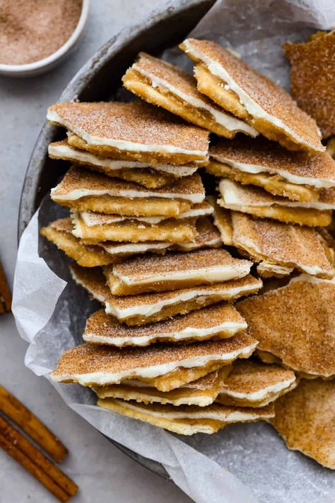 Delicious and addicting, Churro Crack is a base of saltine crackers layered with toffee and creamy white chocolate, then topped with a mix of cinnamon and sugar for the most amazing sweet and salty treat. Churro Cracker Candy 12 Tomatoes, Saltine Cracker Churro, Cracker Dessert Recipes Saltine, Churro Cracker Toffee, Sweet And Salty Christmas Treats, Churro Saltine Toffee, Churro Saltine Cracker Toffee, Salty Christmas Treats, Sweet And Salty Desserts