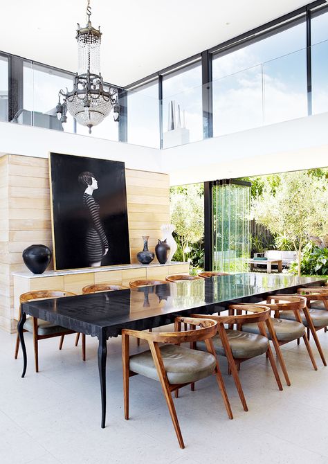 Dining space with white floors, black table, wooden chairs with leather cushions, light wood wall, glass wall, black an white wall art, large chandelier, and black vases Kitchen Materials, Zen Wall Art, Hand Painted Walls, Black Table, Large Abstract Painting, Dining Kitchen, The Dining Room, Large Abstract, Home Interiors