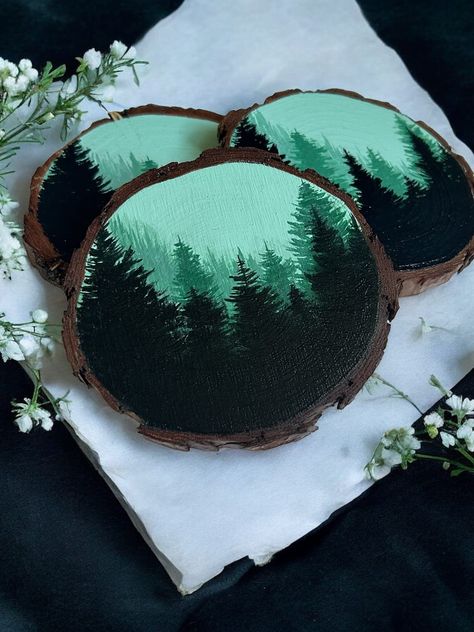 Set of 4  Hand Painted Misty Forest Coasters *For individual coasters, please see other listing located on my shop page* Bring the serenity and magic of a rainy, misty day in the forest into your home with these natural wood coasters featuring a hand painted moody and misty forest scene. Each natural wood coaster is handcrafted with care and measures 3-4 inches. Every coaster top is sealed with water resistant varnish to ensure years of use and has a cork bottom to protect your countertops and t Painted Coaster Ideas, Painted Coasters, Wood Slice Art, Diy Canvas Wall Art, Homeschool Crafts, Misty Forest, Cute Canvas, Wooden Christmas Ornaments, Easy Diy Art