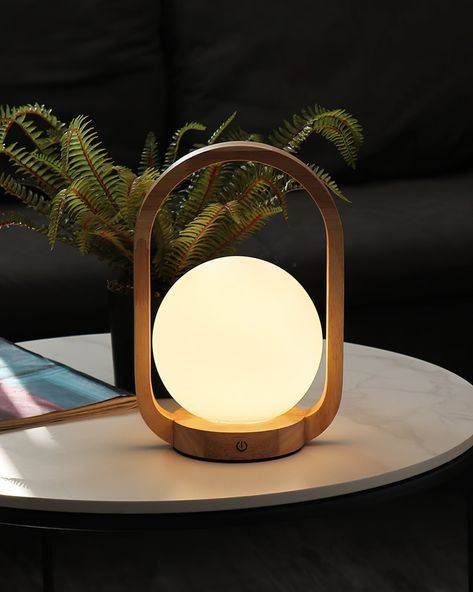 The Audo Wooden Portable Table Lamp is a beacon of serenity, elegantly crafted to bring a tranquil glow to any room. Its design features a smooth wooden arch, encircling a frosted globe that diffuses light into a soft, comforting embrace. Ideal for creating an atmosphere of calm and warmth, this lamp is not just a lighting solution but a piece of decor that complements a peaceful and modern aesthetic.   Purchase Notes:  Only supports shipping to Japan, Australia, the EU, and the United States, a Japandi Lighting, Japandi Lamp, Portable Table Lamp, Wooden Arch, Japandi Interior, Energy Efficient Design, Portable Table, Color Changing Lights, Table Lamp Design