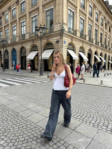 Girls outfit inspo aesthetic paris parisian architecture french buildings black and white crossing putfit insporation french girl red bag black cargos white top jewellery cigarette summer in paris european summer travel travelling girls outfit #paris #outfit #outfitinspo #itgirl #europe #aesthetic Red Designer Bag Outfit, Black Bag Outfit Summer, Vintage Red Bag Outfit, Red Handbag Outfit Street Style, Spring Outfits Germany, Red Purse Outfit Casual, Prague Fashion Summer, Red Bags Aesthetic, Red Bags Outfit