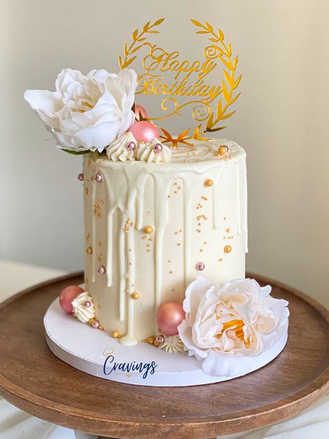 Small cake with white buttercream and white drip, covered in mini and medium sized gold sprinkle balls. Too left and bottom right of the cake has two white artificial flowers resembling a rose accompanied by rosettes of white buttercream and a big pink spherical decoration ball (made of chocolate). On top of the cake is a good cake topper saying “Happy Birthday” positioned on the top right of the cake right next to the flower on the top left. Cake With Artificial Flowers, Artificial Flower Cake, Drip Cake Birthday, Flower Cake Design, Cake Birthday Cake, Flowers Cake, Drip Cake, Mini Cake, Little Cakes