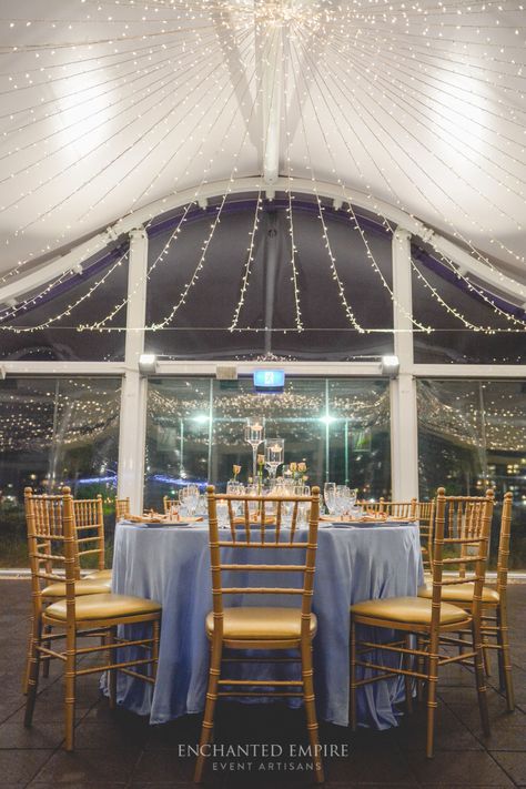 Under a canopy of fairylights this powder blue and gold wedding was the perfect style for this riverside location. Upon custom floor length satin linen, sat an array of floating candles, mercury gold vases filled with white blooms and bud vases, cradling rose stems to add a romantic whimsy to the dining space. Custom stationary kept the rose theme consistent with table numbers and individual thank you notes with an added bomboniere. Youtube: www.youtube.com/watch?v=2-cqj3D3WAc Enchanted Empire Blue Grey Wedding, Hotel Wedding Receptions, Blue And Gold Wedding, Riverside Wedding, Blue Gold Wedding, Riverside Weddings, Custom Stationary, Rosé Theme, Grey Wedding