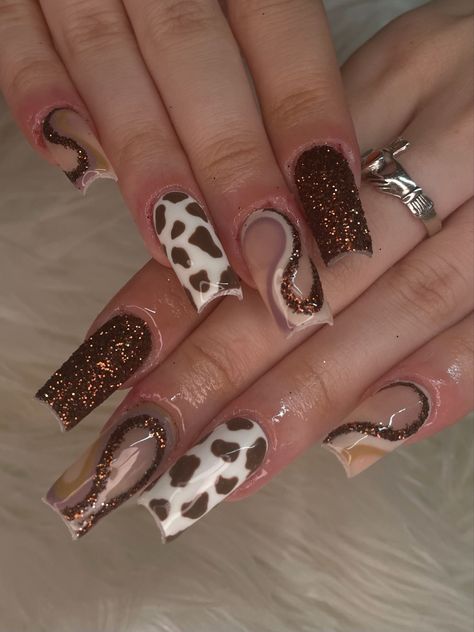 rown nails, brown glitter nails, cow print nails, brown nails, fall nails, luxury nails, sugar glitter nails, swirl nails, trendy nails, square nails, 2023 nails, y2k nails, nail art, nail inspo, gelx nails, gel extensions, baddie nails, hand painted nails, nail artist, brown swirl nails, abstract nails, nail set, funky nail set, nail set inspo, detailed nail art Brown Cow Print Nail Designs, Fall Nails Cow Print, Cow Fall Nails, Brown Square Nails Design, Brown Western Nails, Y2k Fall Nails, Brown Nails With Rhinestones, Cow Print Nails Brown, Square Nails 2023