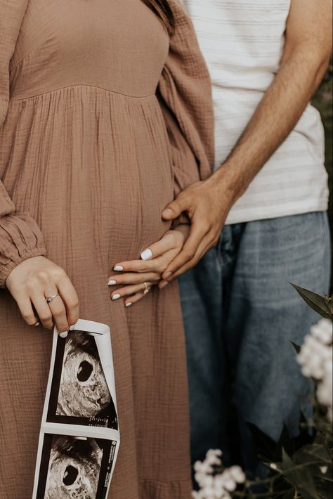 Man holding woman’s hand over her belly over her pink dress, in the womans other hand holds and ultrasound, the picture cuts off right before their heads Things To Do With Ultrasound Pictures, Maternity Pictures With Ultrasound, Maternity Shoot Ultrasound, Maternity Pictures Ultrasound, Pregnancy Announcement Pictures Without Ultrasound, Maternity Shoot With Ultrasound, Studio Baby Announcement, Backyard Pregnancy Announcement, Maternity Photography Ultrasound