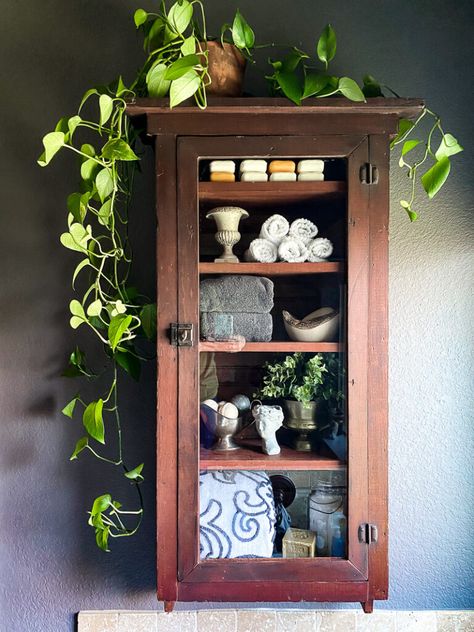 a thrifted cabinet found at a garages sale is perfect for a cozy bathroom upgrade, come see how I decorated this garage sale cabinet for function and style. #bathroomdecor #vintagebathroomstyle #cozybathroom Cozy Vintage Home, Antique Wall Cabinet, Dark Home Aesthetic, Wall Cabinets Living Room, Vintage Bathroom Cabinet, Small Curio Cabinet, Small Bathroom Cabinets, Vintage Medicine Cabinets, Vintage Style Bathroom