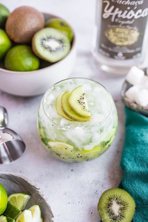 a cocktail topped with kiwi slices surrounded by a bowl of limes and kiwi Caipirinha Cocktail, Tequila Cocktails, Sparkling Water, Limes, A Bowl, So Happy, Tequila, Kiwi, Warm Weather