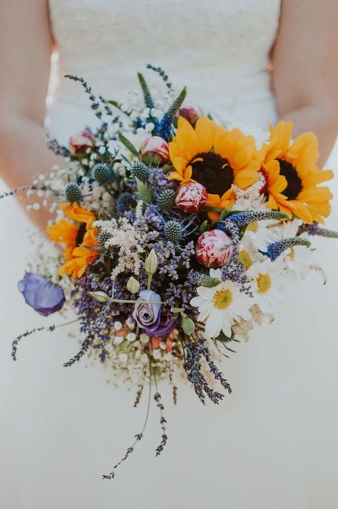 Bride wearing a white wedding dress holding a bouquet of multi colored flowers. Daisy Bouquet Wedding, Wildflower Wedding Bouquet, Colorful Wedding Bouquet, Wedding Flowers Sunflowers, Sunflower Wedding Bouquet, Sunflower Themed Wedding, Sunflowers And Daisies, Summer Wedding Bouquets, Daisy Wedding