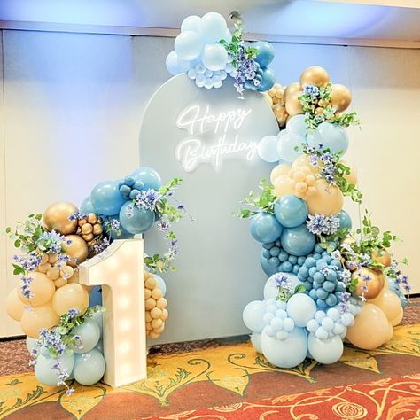 Celebrate your little one’s 1st birthday in the most adorable way by setting up a lovely backdrop. Arrange round top Chiara backdrop stand with light blue spandex cover and brighten it up with neon “Happy Birthday” lights. Add a dash of colorful floral charm by arranging light blue, metallic gold, blue, & peach balloon garland and insert light blue daisies, dahlias, & wisteria vines. Spread cheer and sparkle by placing Marquee number signs in front and give your space a celebratory feel. Blue And Yellow Balloon Garland, Happy Birthday Lights, Birthday Party Backdrop Ideas, Peach Balloon Garland, Gold Wedding Reception Tables, Birthday Backdrop Ideas, 1st Birthday Backdrop, Wisteria Vines, Chiara Backdrop