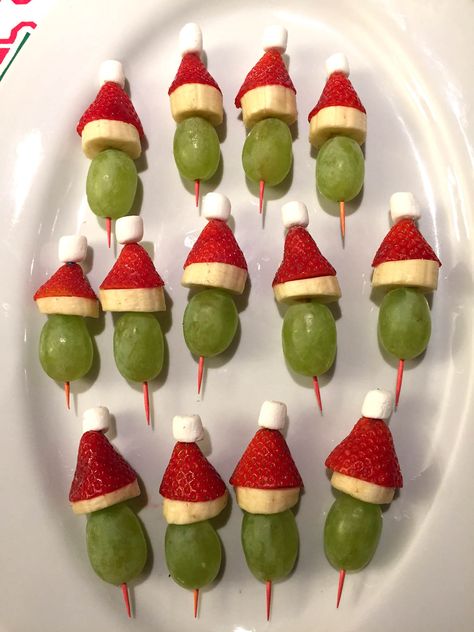 These adorable Grinch Fruit Kabobs will be a hit at your Christmas party!  Made with grapes, strawberries, bananas and marshmallows, these cute little skewers are so healthy and delicious! What's a better thing to do to the evil Grinch who stole Christmas than to eat him?  These little Grinches in Santa hats are made using the green grape for the Grinch face, and the strawberry, banana and mini marshmallow for the Santa hat!  These Crinch fruit kabobs are so cute and delicious, everyone l... Grinch Fruit Kabobs, Grinch Kabobs, Fruit Kabob, Healthy Christmas Snacks, Strawberry Santas, Fruit Appetizers, Kabob Skewers, Fruit Kabobs, Christmas Fruit