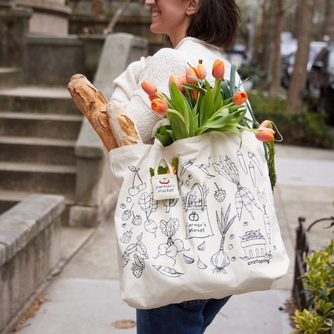 We made a bag with our friends at Winter Water Factory! Cut, Sewn and Printed down the street from us in Winter Water Factory's local Brooklyn studio, this fun oversized tote features illustrations of our new fruit and veggie ornaments. Check out more from Winter Water Factory here. Made locally in Brooklyn with up-cycled cotton canvas. Features black line illustrations of our Farmer's Tote Bag Ornament, Pick Your Own Blueberry Basket, Strawberries, Cherries, Beaded Peapod, Carrot, Radish, Garli Basket Strawberries, Blueberry Basket, Garlic Corn, Tote Bag Illustration, Farmers Market Aesthetic, Farmers Market Tote Bag, Water Factory, Winter Tote, Line Illustrations