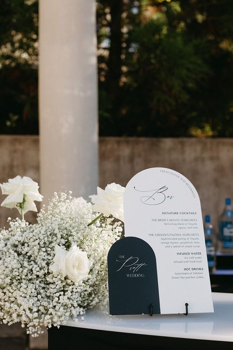 All White Wedding Flowers Receptions, Modern Black And White Wedding Signage, Bar Decor Wedding Receptions, Classic Wedding Ceremony Decor, Wedding Signs Bar, Wedding Sign Florals, Monochromatic Wedding Flowers, White Wedding With Black Accents, Bar Florals Wedding