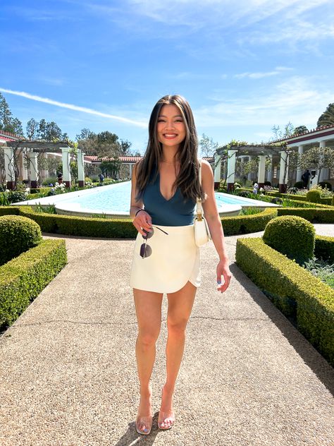 Girl wearing white skirt and teal bodysuit at Getty Villa Skorts Skirts Outfit Ideas, Deep V Bodysuit Outfit, Zara Skort Outfit, Zara Bodysuit Outfit, Skort Outfit Elegant, Nude Bodysuit Outfit, White Skort Outfit, Clear Heels Outfit, Outif Ideas