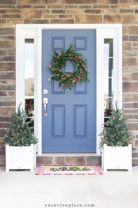 Use these simple Christmas porch ideas to add a welcoming touch to your home. Includes touches of red, tiny wreaths, and a layered doormat. Periwinkle Front Door, Stairway Garland, Outdoor Fall Decor Ideas, Blue Front Door, Door Colors, Door Paint Colors, Pig Decor, Sutton Place, Painted Front Doors