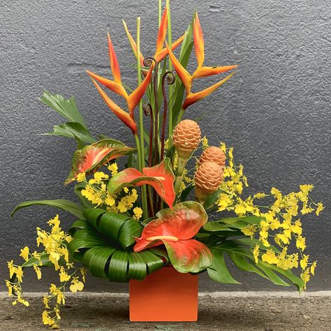 Leanne creates a lavish arrangement with flowers from Green Point Nurseries in this how to floral design video. A ceramic container filled with floral foam and reinforced with chicken wire and waterproof tape to accommodate the heavier stems is the base for a beautiful collection of heliconia, oncidium orchids, anthurium, fern curls, beehive ginger, monstera leaves, fishtail fern, bamboo, Ti leaves and rafus palm. The finished arrangement is a spectacular tropical flower design. Enjoy! Heliconia Arrangement, Beehive Ginger, Tropical Arrangements, Space Environment, Oncidium Orchids, Floral Art Arrangements, Tropical Floral Arrangements, Tropical Flower Arrangements, Tropical Florals