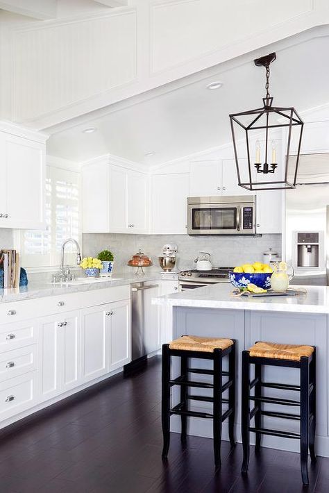 A white sloped ceiling stands over a white shaker kitchen cabinets paired with marble countertops and a marble tiled backsplash. Kitchen Cabinets To Ceiling, Cabinets To Ceiling, Vaulted Ceiling Kitchen, White Shaker Kitchen Cabinets, Ceiling Kitchen, Marble Counters, White Shaker Kitchen, Shaker Kitchen Cabinets, Beach House Kitchens