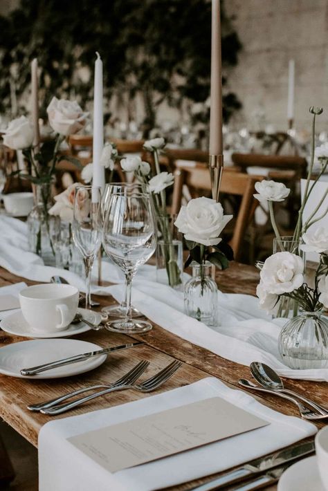 25+ Modern Monochromatic Wedding Florals & Decor Ideas • VintageBash Candle And Floral Tablescape, White Roses In Vase Table Flowers, Cheesecloth Runner Bud Vases, Wedding Neutral Table Setting, Head Table Bud Vases And Candles, Muslin Table Runner Wedding, Bud Vase Table Setting, Long Table Wedding Set Up, White Bud Vases Wedding Centerpiece