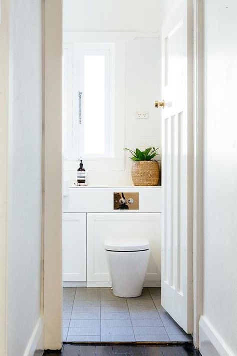 Modern bathroom features a wall-mount toilet atop a gray grid floor placed under windows. Toilet Under Window, Window Above Toilet, Powder Room Modern, Above Toilet, Cheap Patio Furniture, All White Bathroom, Shelves Over Toilet, Bathroom Shelves Over Toilet, Moving Apartment